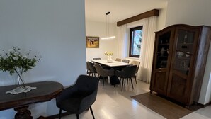 Un coin repas comprenant une table, des chaises, un buffet et un vase avec des fleurs.