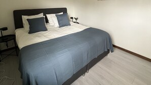 Une chambre à coucher comprenant un lit, une table de chevet, une lampe et une œuvre d’art accrochée au mur.