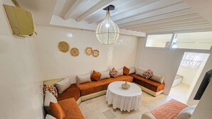 A modern living room with a sectional sofa, a round coffee table, and decorative wall art. - SUPERB 2 BED TERRACE APARTMENT GUELIZ MARRAKECH COMFORT&SERVICES AVAILABLE (Marrakech)