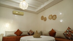 A room with a round table, a sofa, and a hanging light fixture. - SUPERB 2 BED TERRACE APARTMENT GUELIZ MARRAKECH COMFORT&SERVICES AVAILABLE (Marrakech)