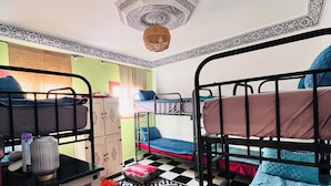 Une chambre de dortoir avec des lits superposés, un sol à motifs et un luminaire au plafond.