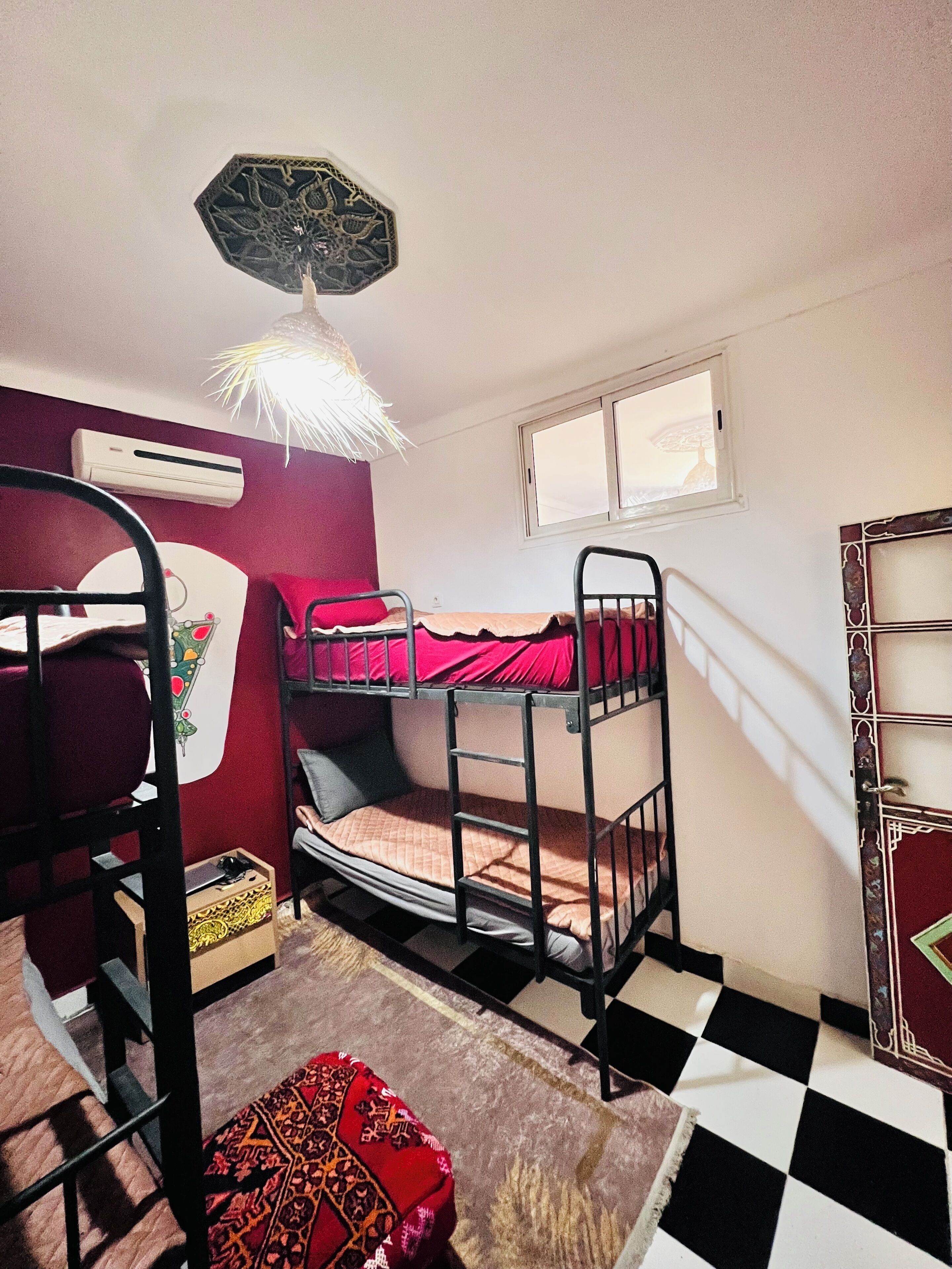 A bunk bed room with a checkered floor, a window, and an air conditioning unit.