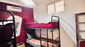 A bunk bed room with a checkered floor, a window, and an air conditioning unit.