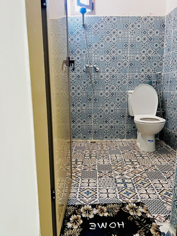 A bathroom with patterned tiles, a toilet, and a shower area. - Pikala Hostel (Marrakech)