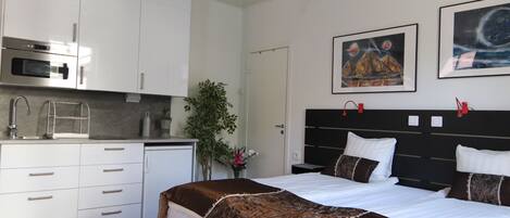 Une chambre d’hôtel moderne équipée d’un lit, d’un bureau et d’une kitchenette.