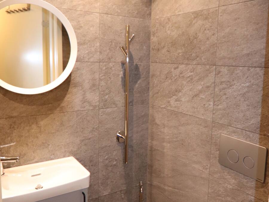 A bathroom with a sink, mirror, toilet, and shower.