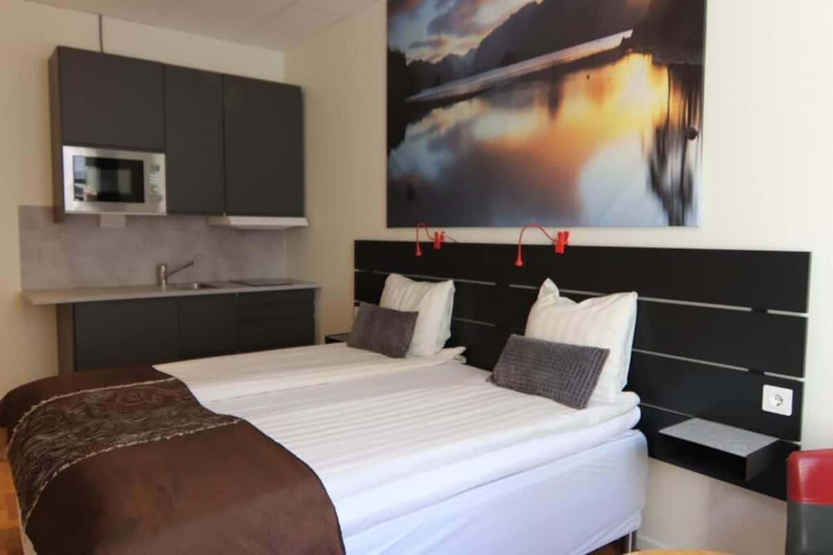 Una habitación de hotel moderna con una cama grande, un escritorio empotrado y vistas al lago a través de la ventana.