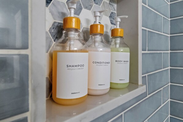 Three bottles of shampoo, conditioner, and body wash on a shelf.
