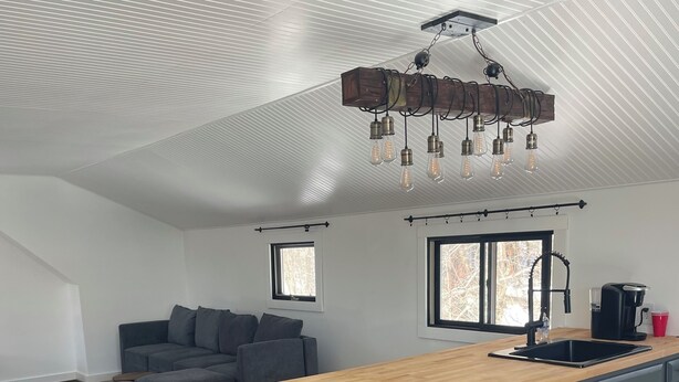 A spacious kitchen with a wooden island, grey cabinets, and a modern pendant light fixture.