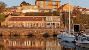 Un immeuble situé au bord de l’eau, doté de nombreux balcons et donnant sur un port de plaisance où sont amarrés des bateaux.
