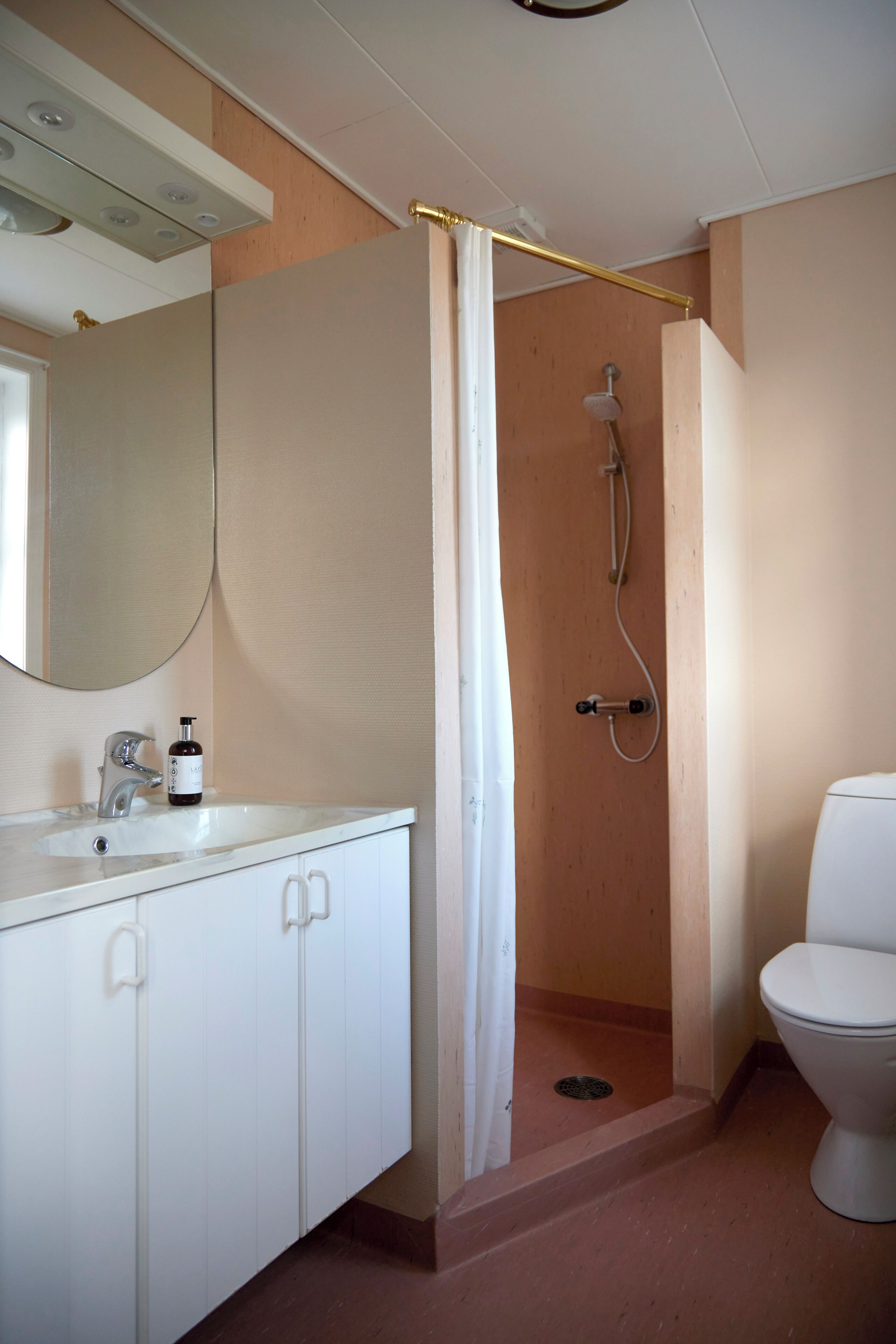 A bathroom with a shower, toilet, sink, and cabinets.
