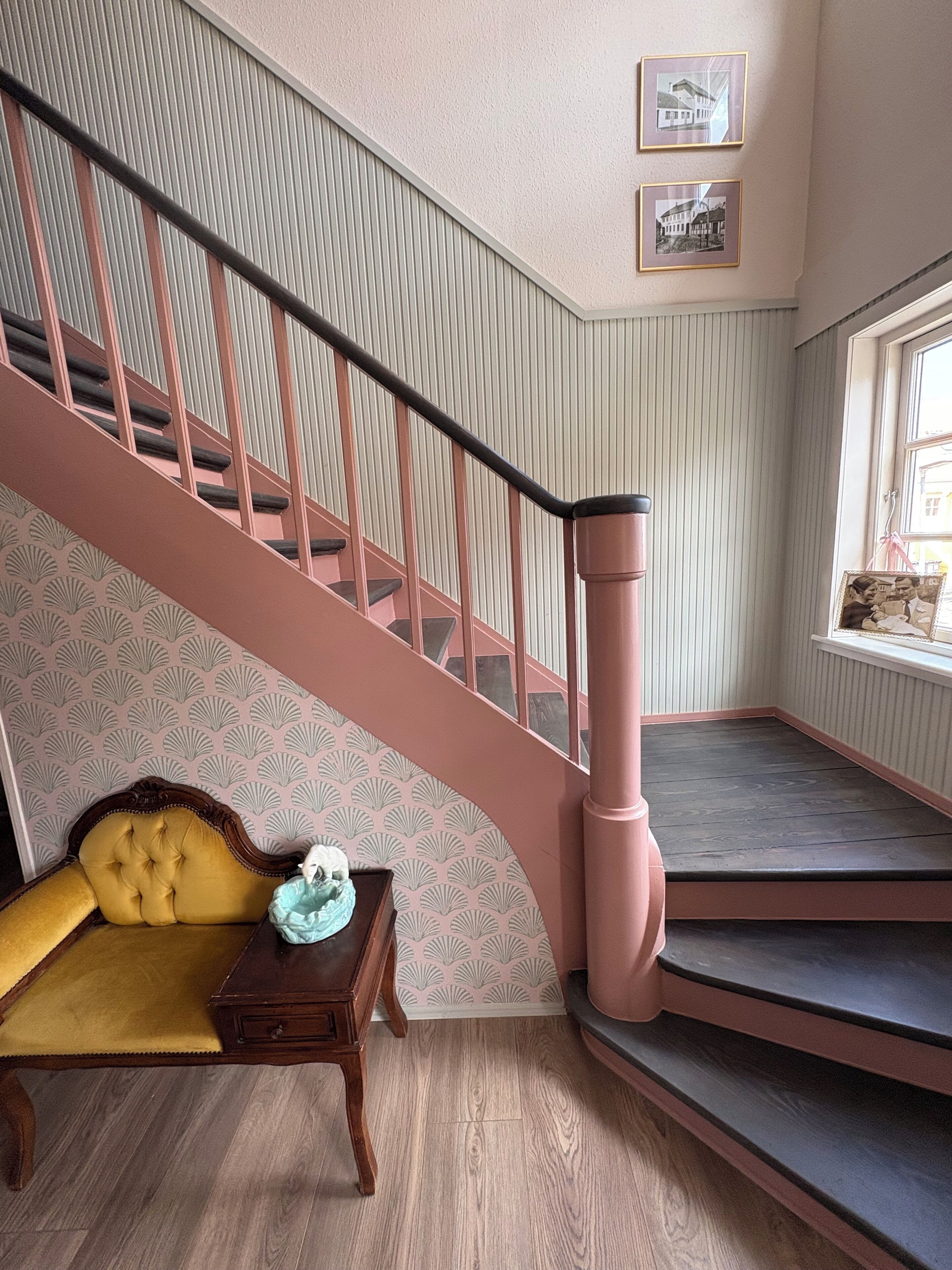 Un escalier avec des rampes roses et un mur orné de motifs.