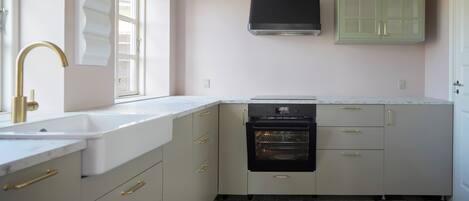 A kitchen with a white countertop, a black oven, and a window with blinds.