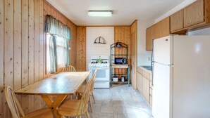 Eine Küche mit Holzausstattung, einem weißen Kühlschrank, einem Herd und einer Mikrowelle.