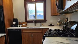 A kitchen with wooden cabinets, a built-in dishwasher, a stove, and a window with a view of the outdoors. - Private, Mountain views, Close to Horse Show Grounds, Lake Placid and Hiking (Keene)