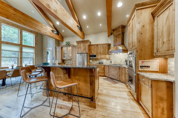 A spacious kitchen with wooden cabinets, a central island, and bar stools.