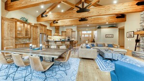 A spacious kitchen with wooden beams, a dining area with a large table and chairs, and a living room with a sofa and coffee table. - 6 Bdrm - Caldera Springs: Lodge on the Pond (Bend)