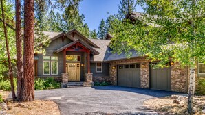 A two-story house with a stone facade, a front porch, and a garage. - 6 Bdrm - Caldera Springs: Lodge on the Pond (Bend)