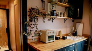 Una cocina con encimera de madera, horno antiguo, fregadero y armarios.