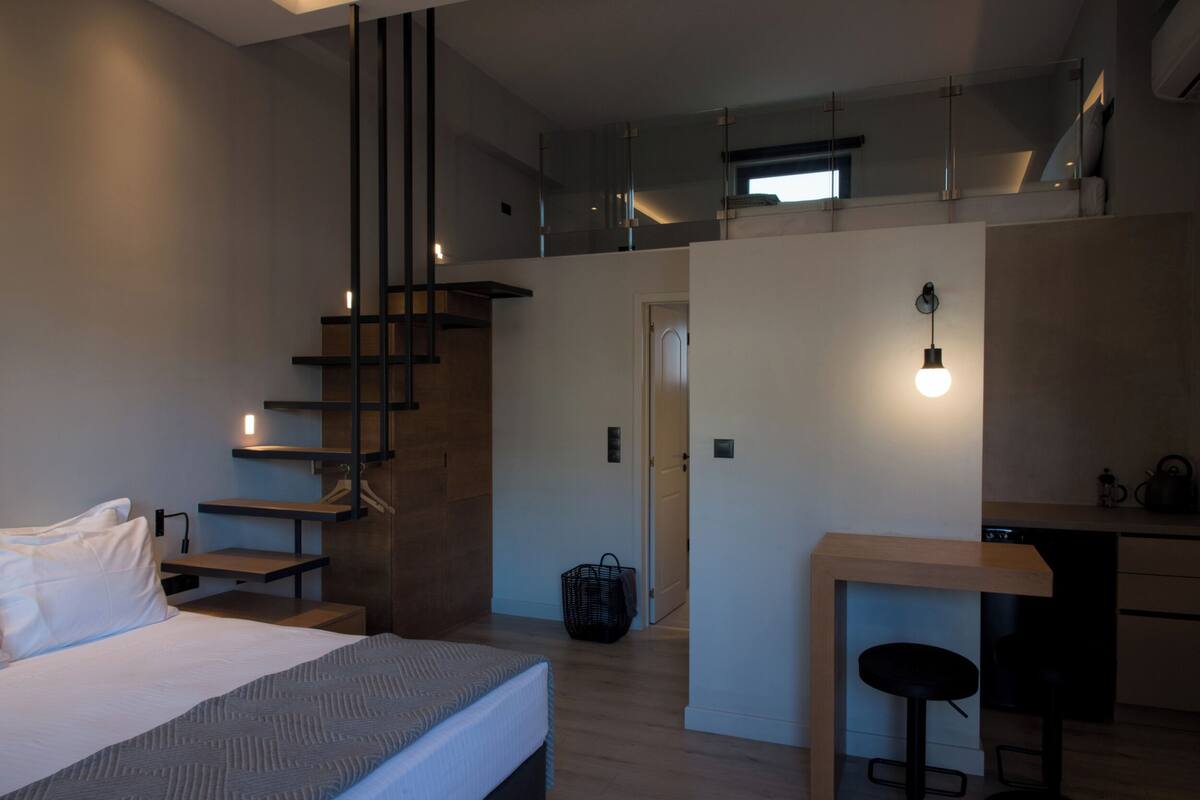 Una camera d'albergo moderna con un letto, una scrivania e una scala.