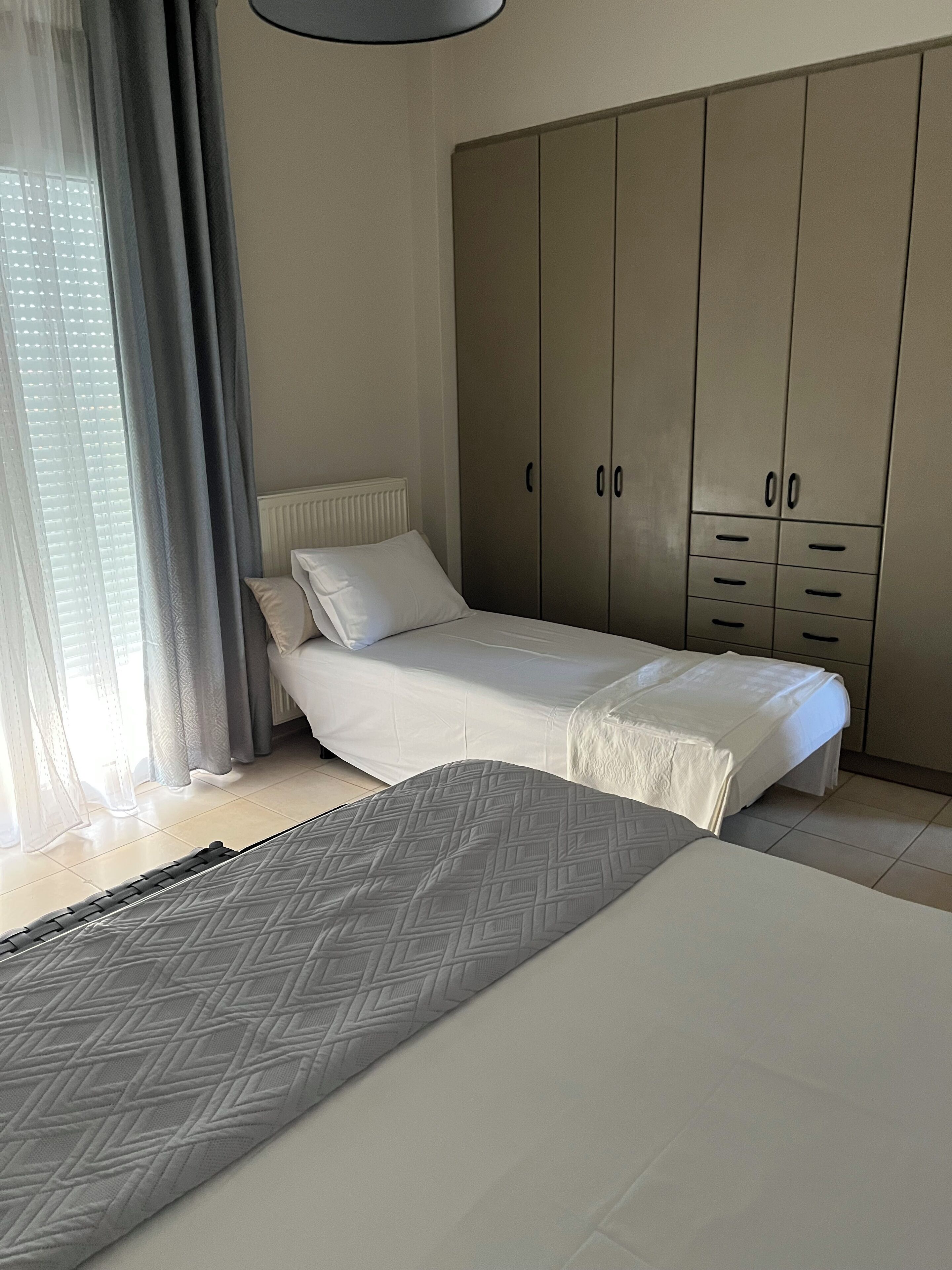 Un dormitorio con cama, armario y ventana con cortinas.
