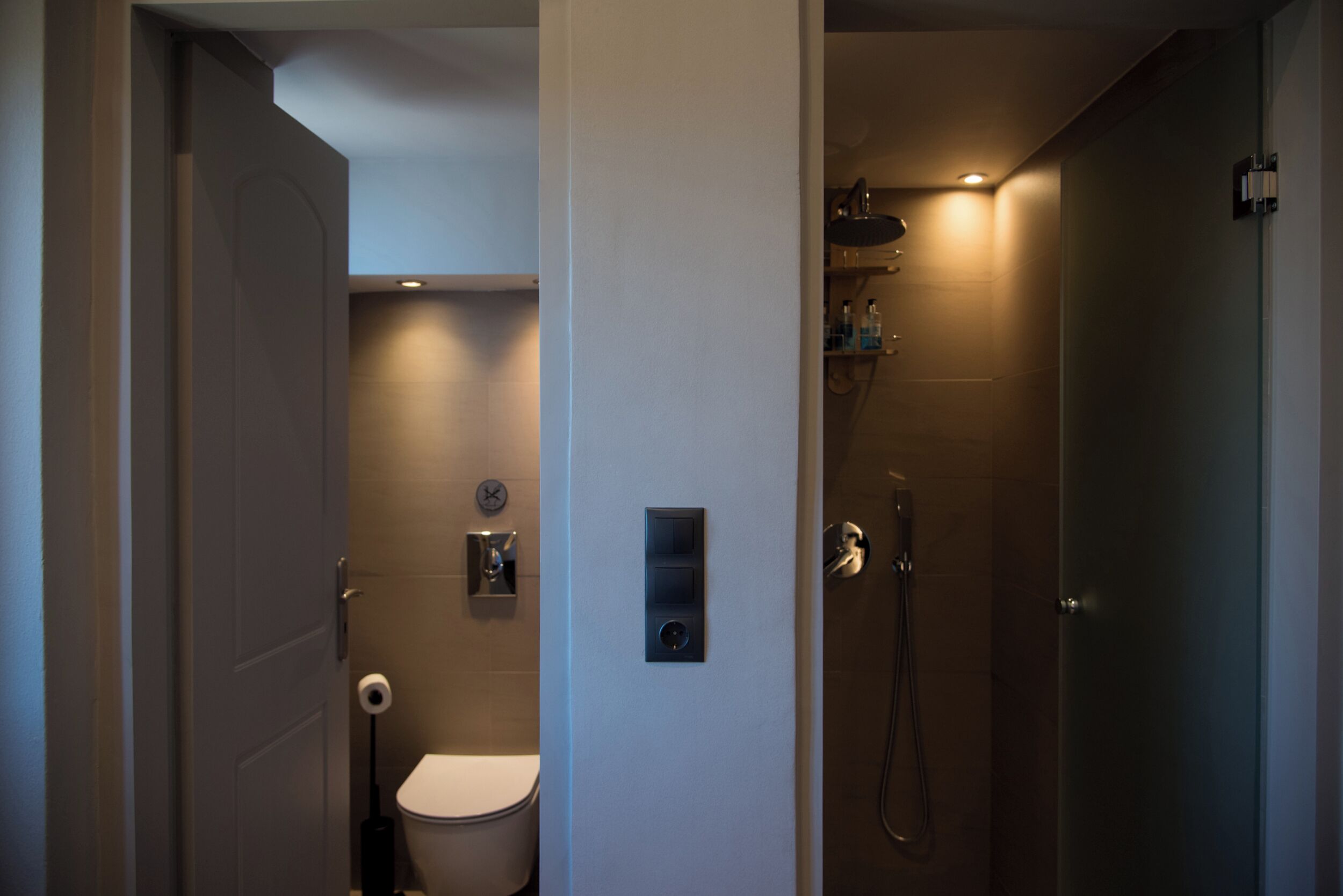 Een moderne badkamer met toilet, douche en wastafel.