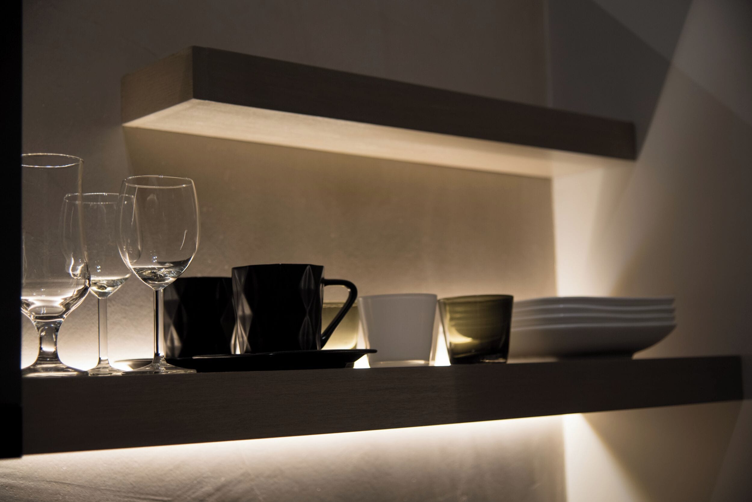 A shelf with various glassware and a bowl, illuminated by a soft light.