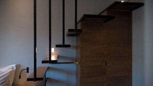 A modern room with a wooden wardrobe, a bed with white bedding, and a hanging light fixture. - ILION Air Host - Near Athens International Airport (Markopoulo Mesogaias)