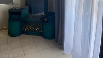 Una habitación con cama, espejo, una mesita y ventana con cortinas.