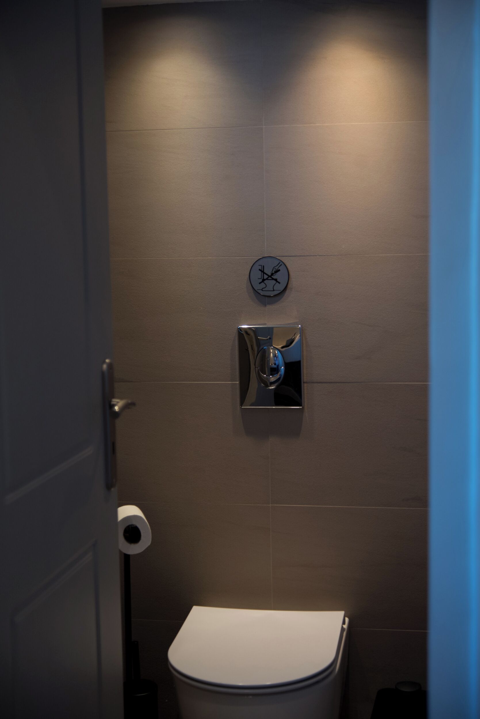 Un baño con inodoro, secamanos y dispensador de toallas de papel.