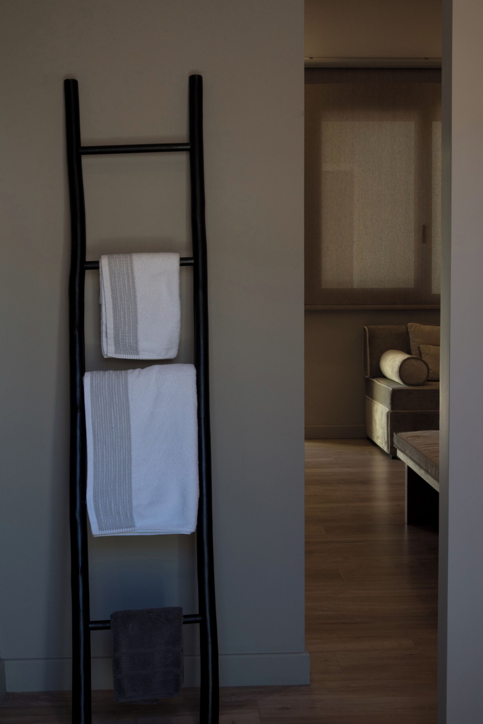A black metal towel rack with three towels against a wall.