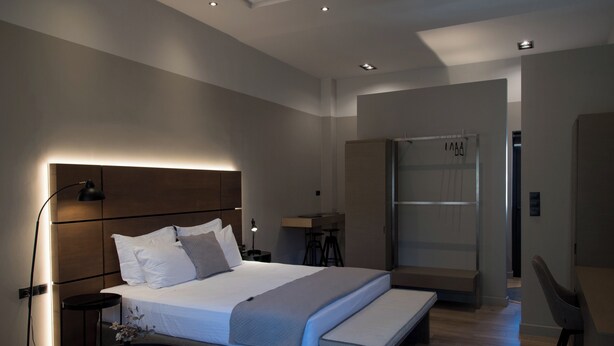 A modern hotel room with a large bed, bedside tables, a desk, and a wardrobe. - ILION Air Host - Near Athens International Airport (Markopoulo Mesogaias)