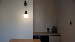 A modern kitchen with a wooden table, a dishwasher, and a kettle on the counter. - ILION Air Host - Near Athens International Airport (Markopoulo Mesogaias)