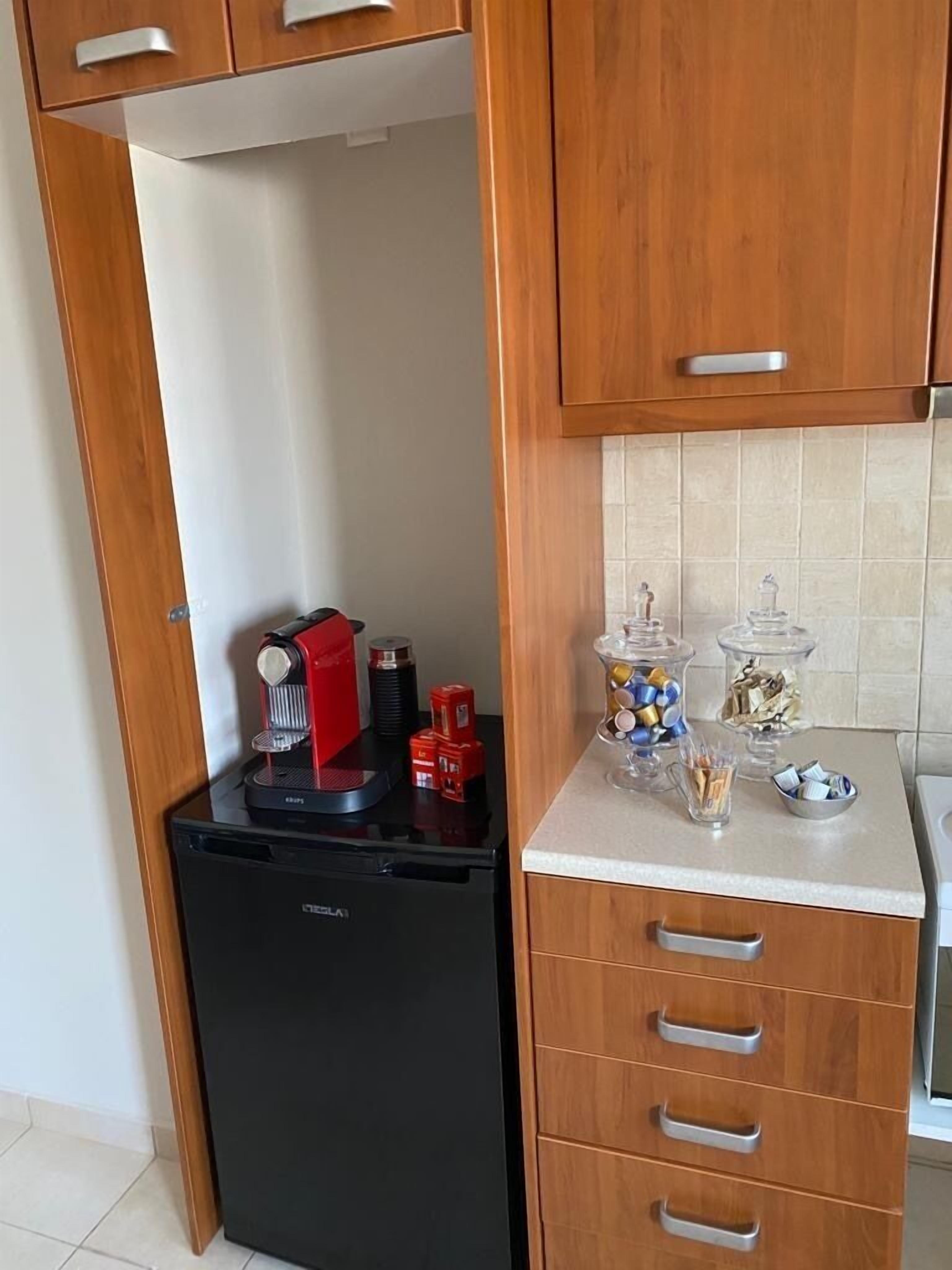 A compact kitchen with a black refrigerator, wooden cabinets, and a countertop with various items.