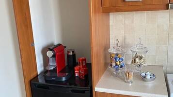 A compact kitchen with a black refrigerator, wooden cabinets, and a countertop with various items.