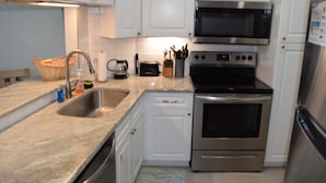 A modern kitchen with white cabinets, stainless steel appliances, a sink, and a toaster. - Beautiful 2-bedroom condo with AC, WiFi and direct beach access in Gulf Shores (Gulf Shores)