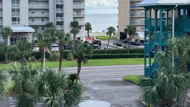 A multi-story hotel with balconies, a covered gazebo, and palm trees. - Beautiful 2-bedroom condo with AC, WiFi and direct beach access in Gulf Shores (Gulf Shores)