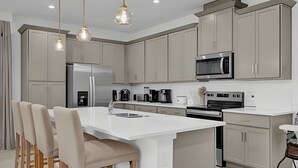 A modern kitchen with a central island, stainless steel appliances, and pendant lighting. - Dream Home at Solara Resort 6BD and Total Comfort (Kissimmee)