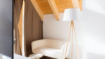 A modern room with a wooden ceiling, a white sofa, a floor lamp, and a small table.