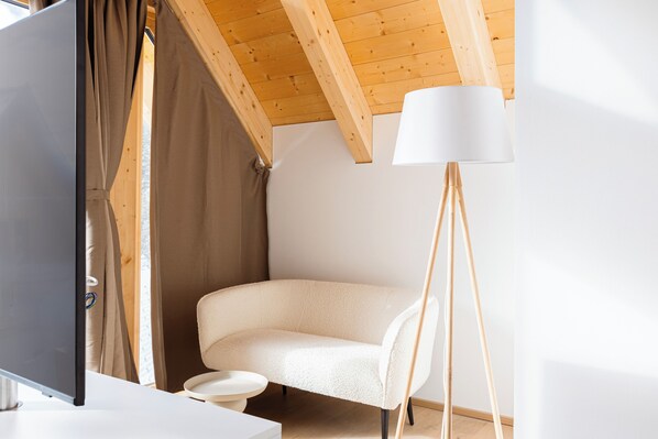 Una habitación moderna con techo de madera, un sofá blanco, una lámpara de pie y una pequeña mesa.