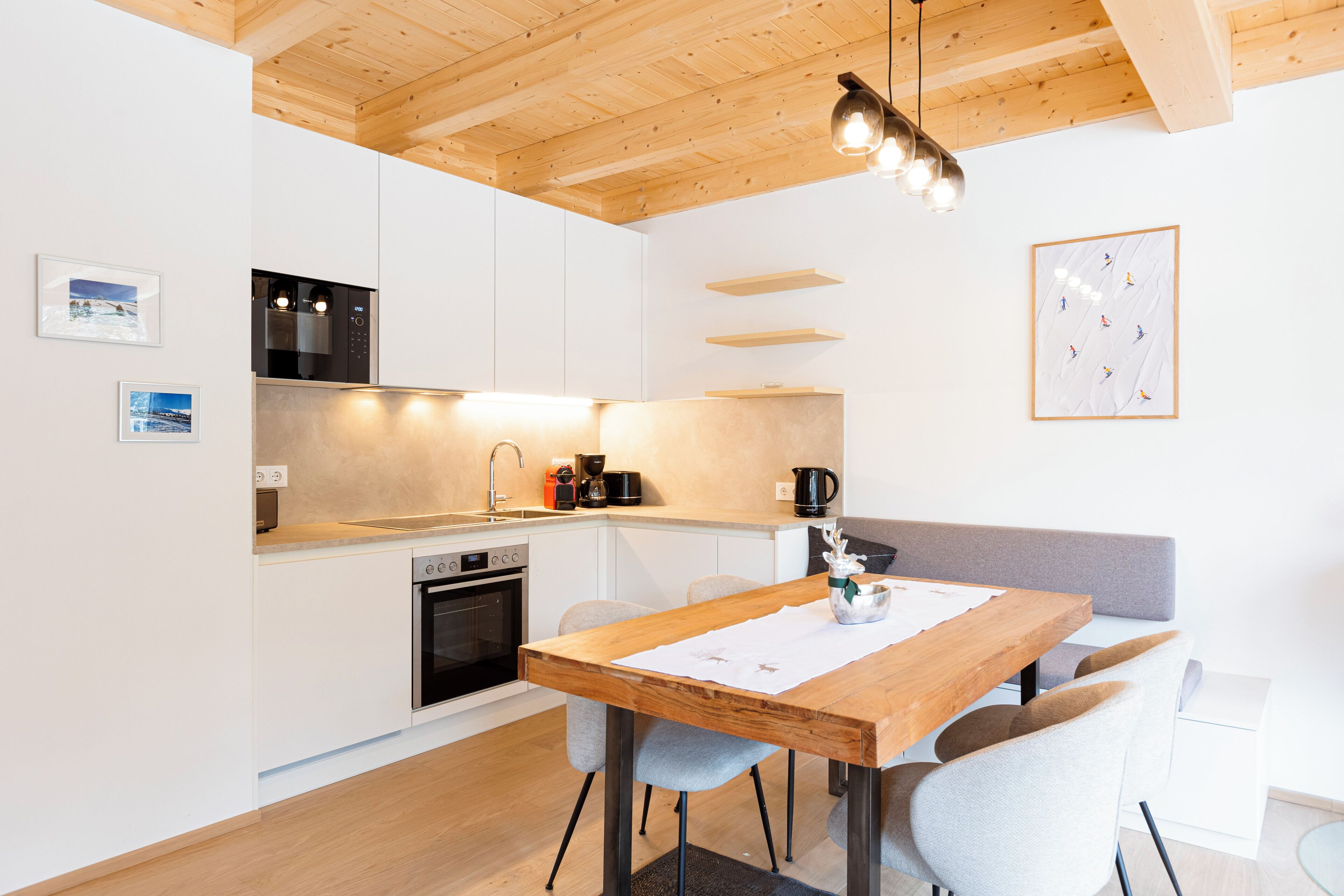 A modern kitchen with white cabinets, a wooden ceiling, and a dining area with a wooden table and chairs.