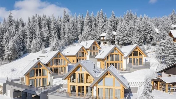 A cluster of wooden cabins with large windows, set against a snowy backdrop with pine trees. - Rehfugium Lachtal by ALPS RESORTS (Oberwölz)