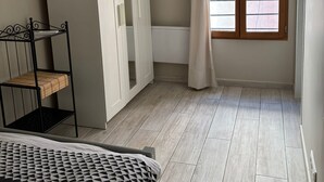 Un dormitorio con cama, armario y ventana con cortinas.