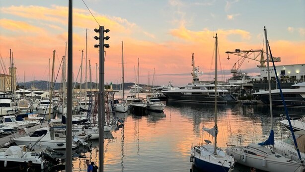 Un puerto deportivo con barcos amarrados, un paseo peatonal y un edificio con la leyenda 'RESTAURANT' al fondo.