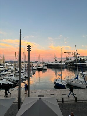 Un port de plaisance avec des bateaux amarrés, une promenade piétonne et, au fond, un bâtiment sur lequel on peut lire l’inscription « RESTAURANT ».