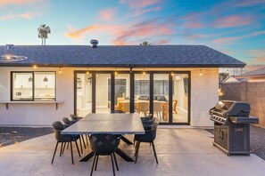 Una casa moderna con un patio, un comedor y una parrilla.