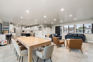 A spacious living area with a dining table, chairs, a sofa, and a coffee table.