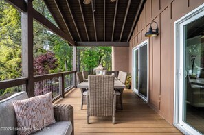 Une terrasse couverte avec une table et des chaises, une lanterne et une porte-fenêtre coulissante.