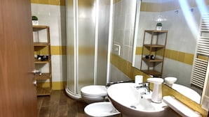 Une salle de bain avec douche, toilettes et lavabo.