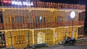 A building with a sign reading "HOTEL PAUL VILLA" and multiple balconies adorned with string lights.